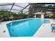 Community pool with screened enclosure, lounge chairs, and clear blue water at 2156 Masters Ct # 2156, Dunedin, FL 34698