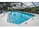 Community pool with screened enclosure, lounge chairs, and clear blue water at 2156 Masters Ct # 2156, Dunedin, FL 34698