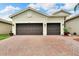Two-car garage with dark brown doors and a brick driveway at 16005 Cape Coral Dr, Wimauma, FL 33598