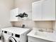 Bright laundry room features washer, dryer, cabinets, and a utility sink at 16005 Cape Coral Dr, Wimauma, FL 33598