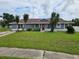 Ranch-style home with gray siding, red door, and palm trees in the front yard at 36131 Pine Bluff Loop, Dade City, FL 33525