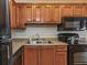 Modern kitchen featuring wood cabinets, black appliances, and double sink at 105 Pompano Se Dr # A, St Petersburg, FL 33705