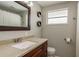 Well-lit bathroom featuring a vanity with dark wood cabinets, tan countertop and framed mirror at 12318 Woodleigh Ave, Tampa, FL 33612