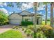Eye-level view of a two-story house with gray exterior, lush landscaping, and a brick driveway at 19501 Sea Myrtle Way, Tampa, FL 33647
