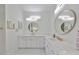 Modern bathroom featuring double sinks, white cabinetry and round mirrors with decorative light fixtures at 415 Islebay Dr, Apollo Beach, FL 33572