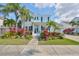 Charming two-story home featuring a beautiful landscaped yard with vibrant tropical plants and palm trees at 415 Islebay Dr, Apollo Beach, FL 33572