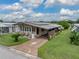 Single-story home with carport and landscaped yard in a mobile home community at 35027 Wagner Way, Zephyrhills, FL 33541
