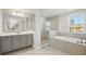 Serene primary bathroom with gray cabinetry, double vanity, soaking tub, and walk-in shower at 3437 Yellow Leaf Cir, Spring Hill, FL 34609