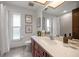 Bathroom featuring cherry wood cabinetry, large mirror, and natural light from two windows at 1105 Deer Run Pl, Valrico, FL 33594