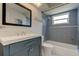 Modern bathroom with gray tile, a white vanity, and a bathtub at 3123 Merita Dr, Holiday, FL 34691