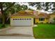 Yellow house with a two-car garage and landscaped lawn at 7519 Harbor View Way, Seminole, FL 33776