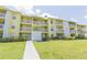 Two-story yellow building with balconies and lawn at 455 Alt 19 S # 175, Palm Harbor, FL 34683