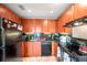 Efficient kitchen with wood cabinets, black appliances, and granite countertops at 5176 Salmon Se Dr # A, St Petersburg, FL 33705