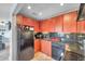 L-shaped kitchen featuring wood cabinets, black appliances, and granite countertops at 5176 Salmon Se Dr # A, St Petersburg, FL 33705