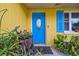 Inviting blue front door and yellow exterior with blue shutters at 1627 Dander Dr, Holiday, FL 34690