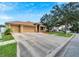 Tan three-car garage home with a red door and nicely landscaped yard at 12739 Standbridge Dr, Riverview, FL 33579