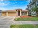 Tan three-car garage home with a red door and nicely landscaped yard at 12739 Standbridge Dr, Riverview, FL 33579