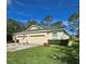 Tan house with green roof, three-car garage, and manicured lawn at 34735 Double Eagle Ct, Zephyrhills, FL 33541