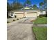 Tan house with green roof, three-car garage, and manicured lawn at 34735 Double Eagle Ct, Zephyrhills, FL 33541