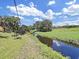 A lovely view of the backyard featuring lush green grass, a tranquil stream, and a vibrant blue sky with clouds at 1385 Embassy Dr, Clearwater, FL 33764
