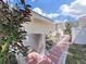 Exterior shot of a home with a brick walkway, landscaped garden beds, and lush greenery at 1385 Embassy Dr, Clearwater, FL 33764