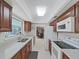 Galley kitchen featuring white countertops, wood cabinets, and modern appliances with a view to the living room at 1385 Embassy Dr, Clearwater, FL 33764