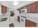 Traditional kitchen featuring wood cabinets, white appliances, and speckled countertops at 1385 Embassy Dr, Clearwater, FL 33764
