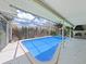 Private in-ground pool surrounded by an enclosed patio and lush landscaping at 1385 Embassy Dr, Clearwater, FL 33764