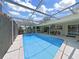 Beautiful screened-in pool area featuring an outdoor dining space, bar, and well-manicured landscaping at 1385 Embassy Dr, Clearwater, FL 33764