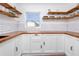 Beautiful kitchen featuring butcher block countertops, white cabinetry, subway tile backsplash, and floating wood shelves at 6619 Livingston N Ave, St Petersburg, FL 33702