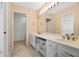 Bathroom featuring double sinks, large mirror with Hollywood lighting, and vanity storage with cabinets and baskets at 9 Pelican Pl, Belleair, FL 33756
