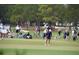 Golf course view features players and spectators gathered on a green with lush trees in the background at 9 Pelican Pl, Belleair, FL 33756