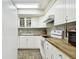 White kitchen with butcher block countertops, mosaic backsplash, and stainless steel appliances at 1655 58Th S Ter # 1, St Petersburg, FL 33712