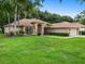 Tan house with a brown roof, landscaping, and a two-car garage at 4940 Willow Ridge Ter, Valrico, FL 33596