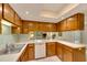 Kitchen with wood cabinets, white appliances, and a view into the dining area at 1400 Tarpon Woods Blvd # B5, Palm Harbor, FL 34685