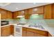 View of kitchen with wood cabinets, white appliances, and a light green backsplash at 1400 Tarpon Woods Blvd # B5, Palm Harbor, FL 34685