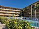 Community pool surrounded by lush tropical landscaping and condo building at 2525 W Bay Dr # B32, Largo, FL 33770