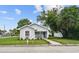 Charming one-story home with light blue siding, a front porch, green lawn and mature trees at 402 E Emma St, Tampa, FL 33603