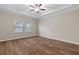Elegant bedroom features tray ceilings, wood flooring, a ceiling fan, and two large windows at 3147 Calvano Dr, Land O Lakes, FL 34639