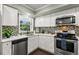Modern kitchen with white cabinets, stainless steel appliances, and mosaic backsplash at 2295 Americus E Blvd # 27, Clearwater, FL 33763