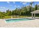 A refreshing community pool with brick pavers and black metal fencing, surrounded by lush greenery and a clear blue sky at 281 Villa Corte Dr, Lutz, FL 33549