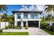 Modern two-story home featuring a black garage door, balcony, and lush tropical landscaping at 2203 Glenwood, Tampa, FL 33602
