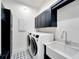 Laundry room with farmhouse sink, washer, dryer, and dark cabinets at 1305 Apollo Beach Blvd, Apollo Beach, FL 33572