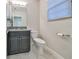 Bathroom with dark vanity, granite countertop, a large mirror, modern fixtures, and a window with blinds at 16850 Whisper Elm St, Wimauma, FL 33598