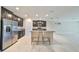 Open kitchen with stainless steel fridge, granite island, and dark cabinets at 16850 Whisper Elm St, Wimauma, FL 33598