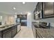 Bright kitchen featuring stainless steel appliances, granite countertops, and sleek dark cabinets at 16850 Whisper Elm St, Wimauma, FL 33598