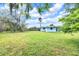 Rear view of a one story home, fence and lush grass in a well-maintained backyard at 233 W College Ave, Ruskin, FL 33570