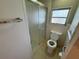 Bathroom featuring glass shower door, open toilet, and handrails at 2331 Belleair Rd # Lot 237, Clearwater, FL 33764