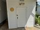 Side exterior storage entrance featuring a thermometer, light fixture, and double flood lights above at 2331 Belleair Rd # Lot 237, Clearwater, FL 33764