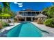 Inviting backyard oasis with a sparkling pool, thatched tiki huts, and lush landscaping at 262 Banana Rd, Palm Harbor, FL 34683